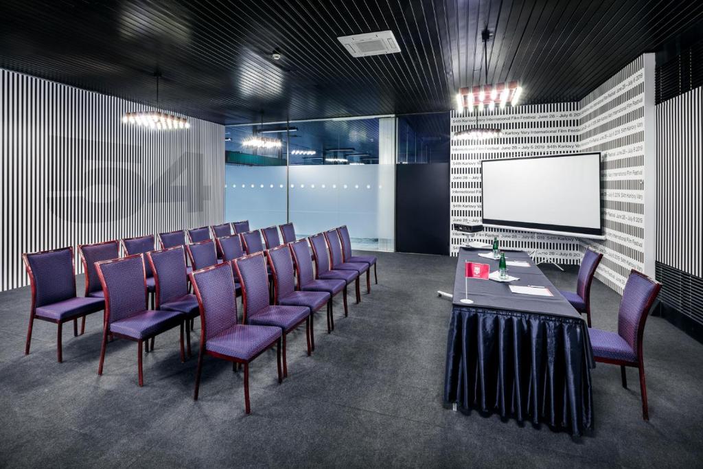 a conference room with purple chairs and a white screen at Hotel Thermal in Karlovy Vary
