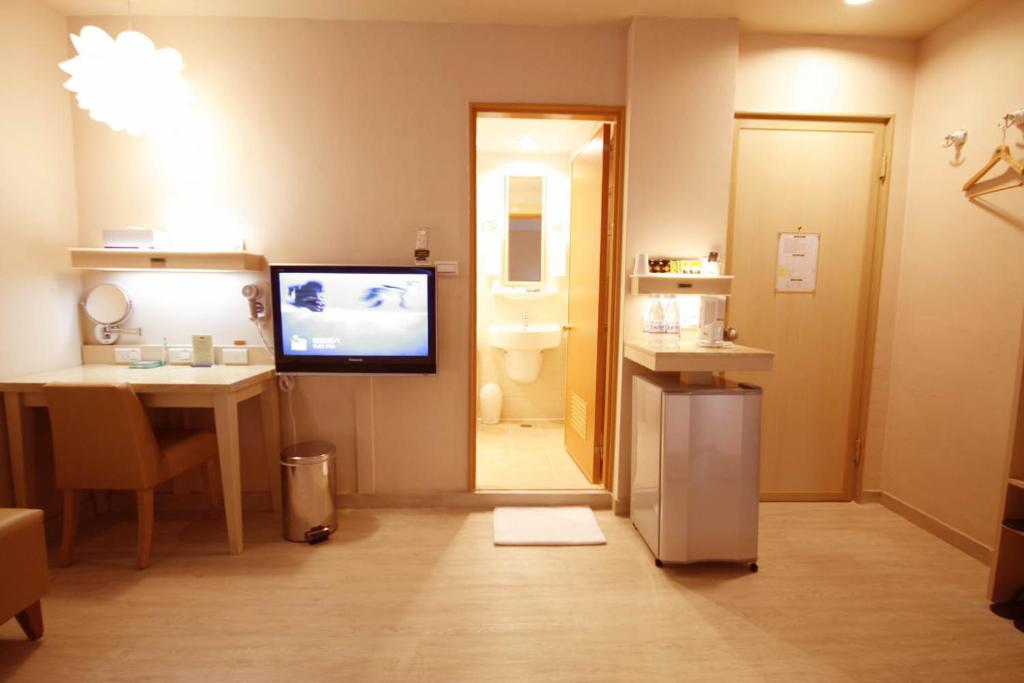 a room with a bathroom with a tv on the wall at Kindness Hotel - Tainan Minsheng in Tainan
