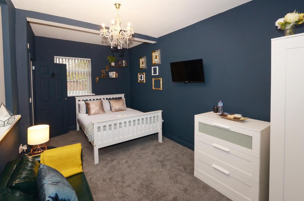 a blue bedroom with a crib and a tv at Townhouse PLUS @ 301 West Street Crewe in Crewe