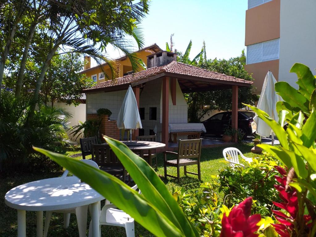 un jardín con mesas y sillas y un cenador en Apart Hotel Ilha Residence, en Florianópolis
