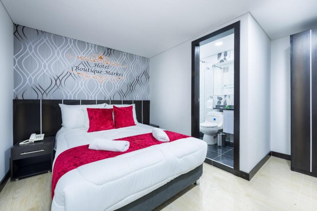 a bedroom with a large white bed with red pillows at Hotel Boutique Markes in Bogotá
