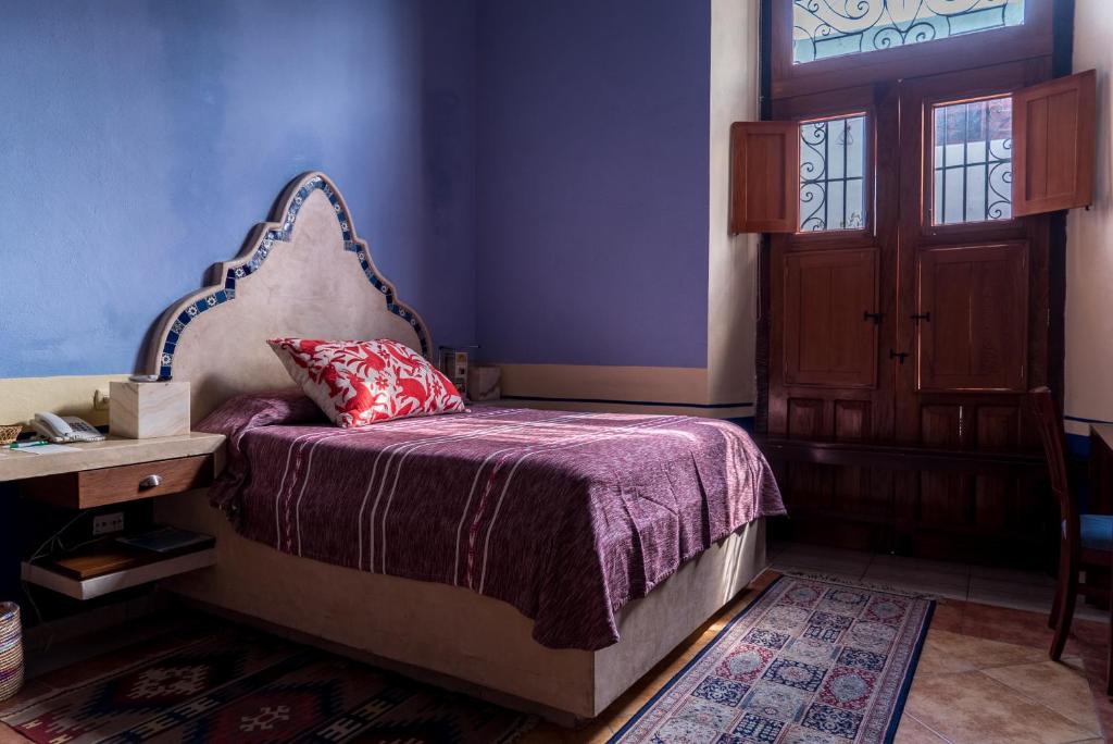 a bedroom with a bed and a wooden door at Hotel Boutique Casa San Angel in Mérida