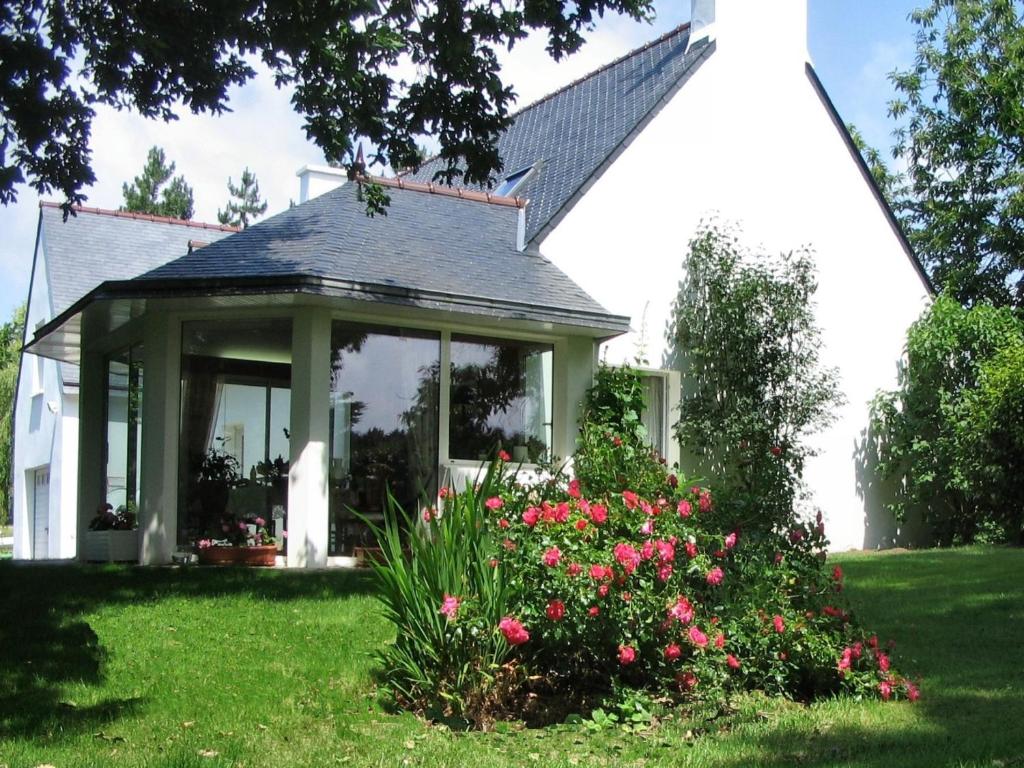 una casa con un cenador con flores en el patio en Chambre d'Hôtes Entre Mer et Monts, en Plomodiern