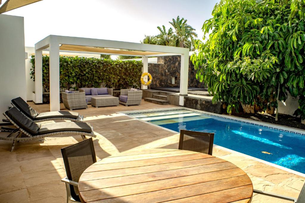 a patio with a table and chairs next to a pool at Casa Yuna with heated pool in El Roque in Cotillo