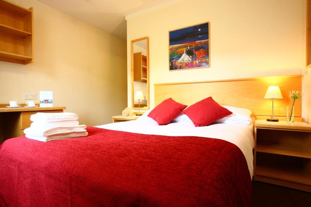 a hotel room with a large red bed with red pillows at Agnes Blackadder Hall - Campus Accommodation in St. Andrews