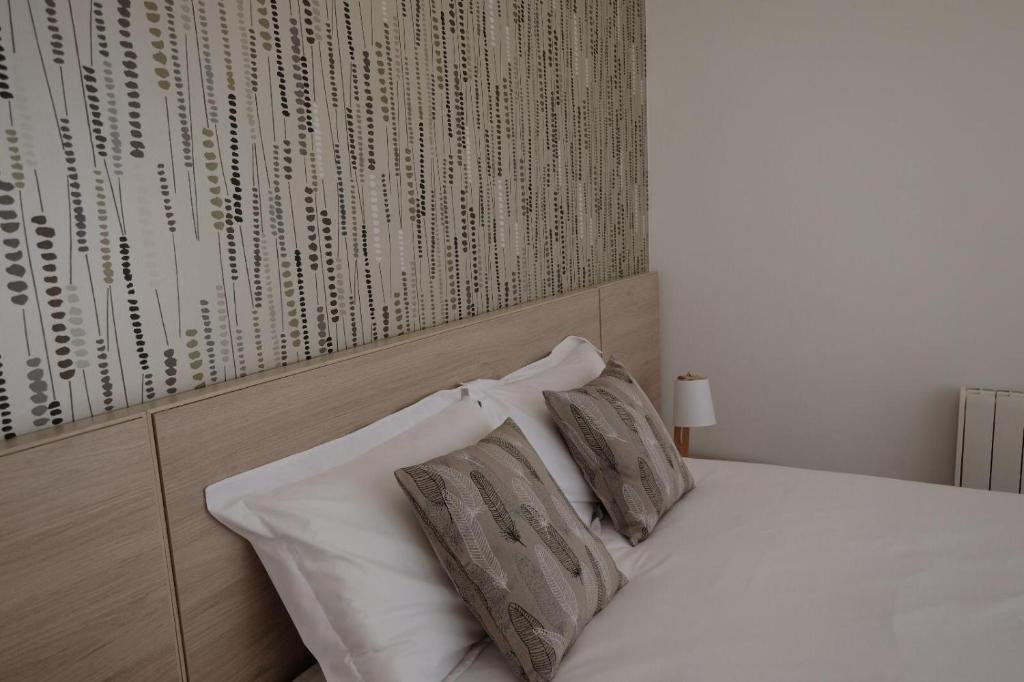 ein weißes Bett mit zwei Kissen und einer Wand mit Inschriften in der Unterkunft Apartamento en el puerto in A Guarda