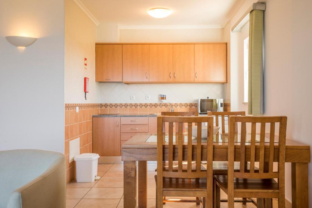 a kitchen with a wooden table and chairs in it at Clube Porto Mos - Sunplace Hotels & Beach Resort in Lagos