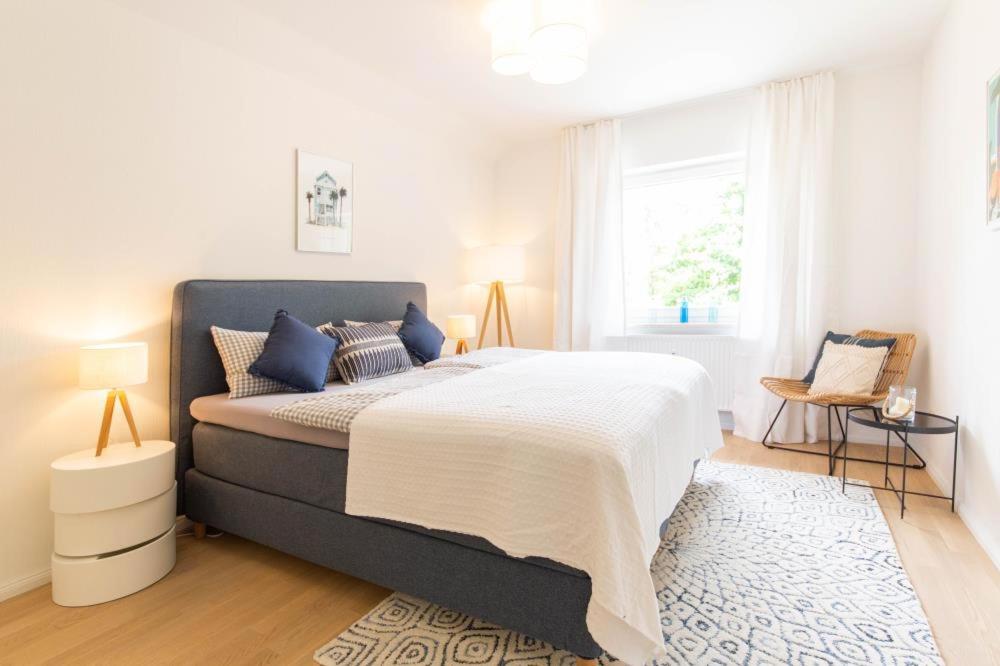 a white bedroom with a large bed with blue pillows at Ferienwohnung Strandallee 18 in Timmendorfer Strand