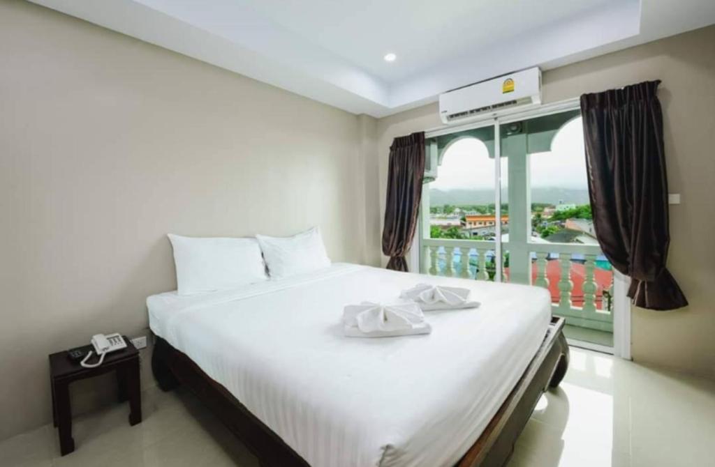 a bedroom with a large white bed with a balcony at Tyler Cherngtalay in Ban Pak Lak
