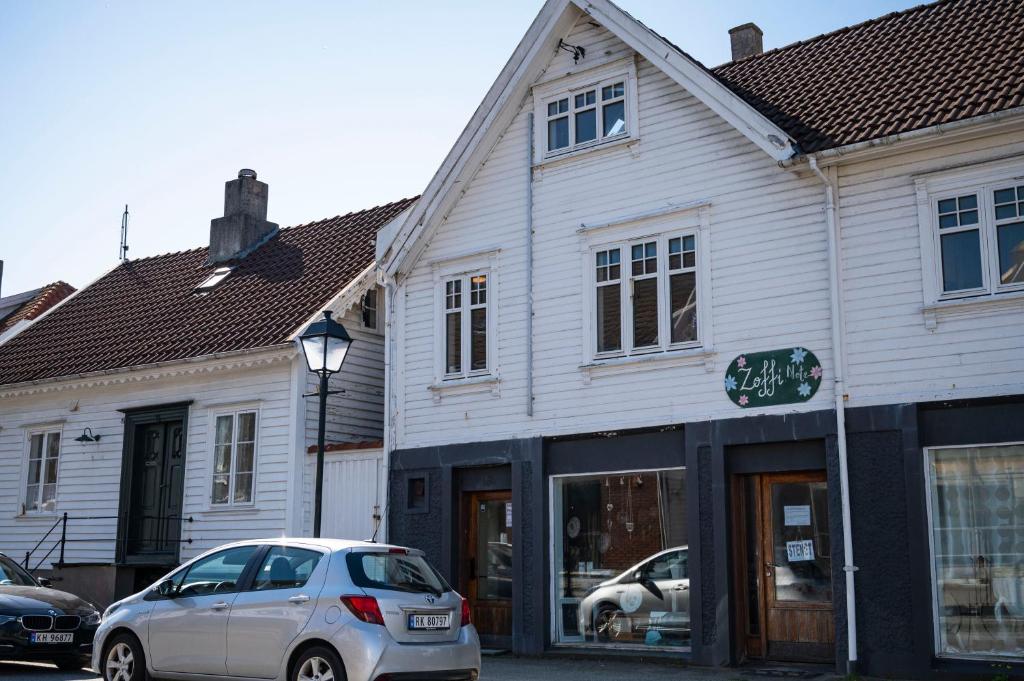 Skudeneshavn的住宿－Idylliske Skudeneshavn，停在白色建筑前的银色汽车