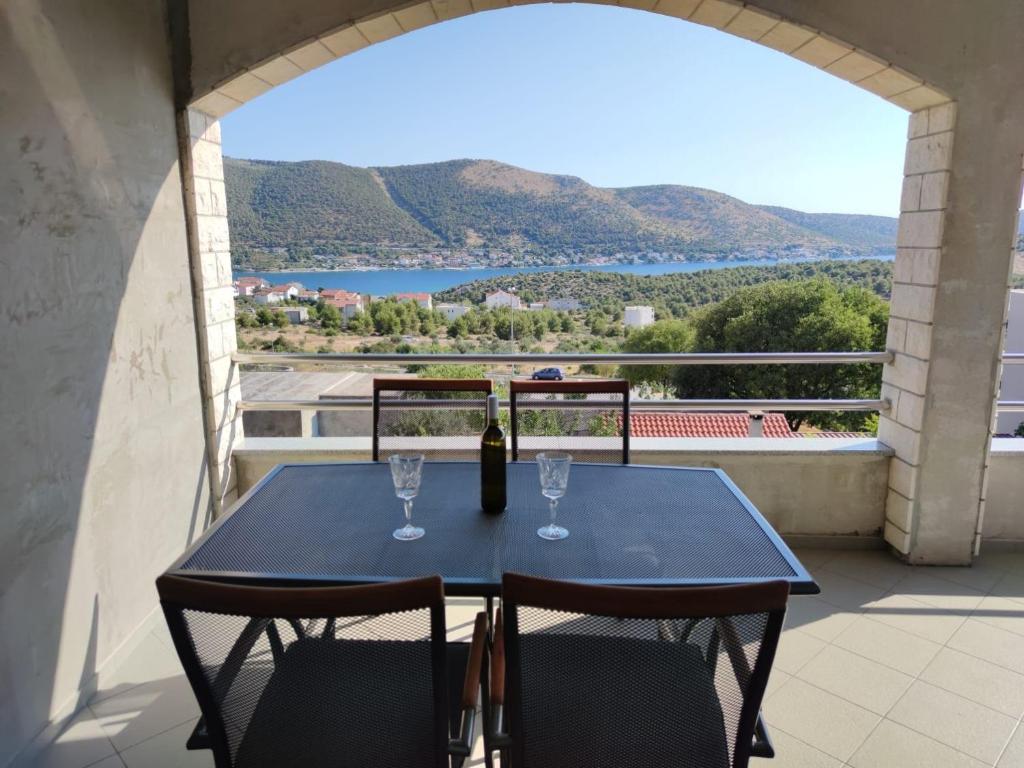 a blue table with two wine glasses on a balcony at Apartments Josi - parking and barbecue in Grebaštica