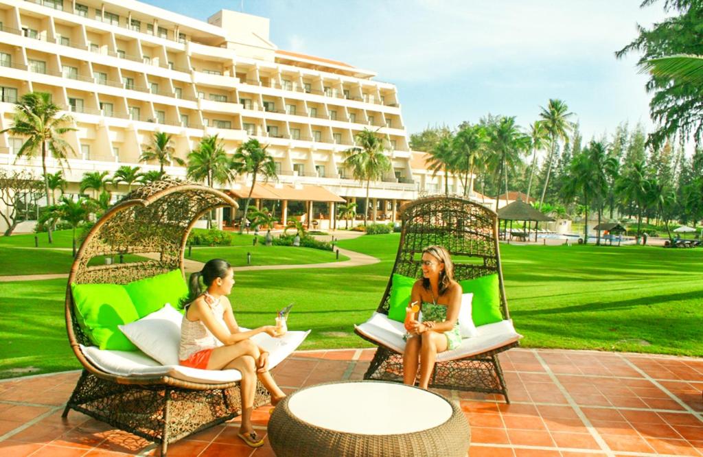 three women sitting in chairs in front of a building at Phan Thiet Ocean Dunes Resort in Phan Thiet