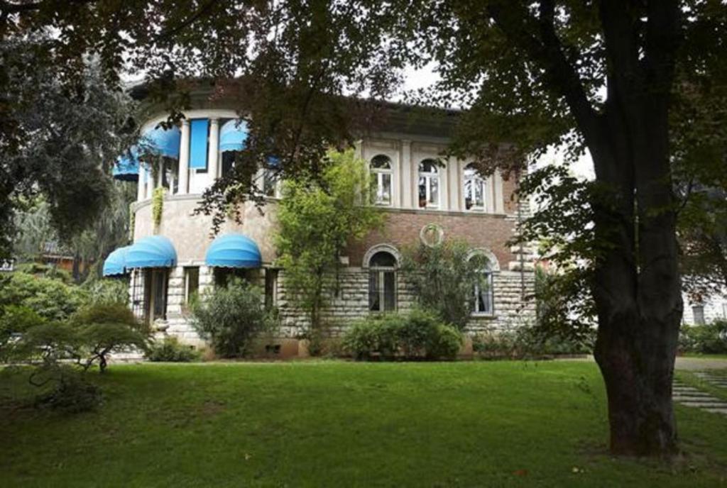 Una gran casa de ladrillo con toldos azules. en Villa V en Brescia