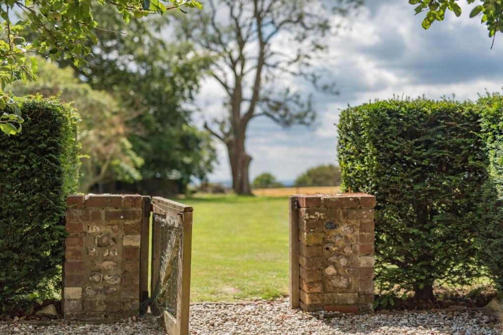 a hedge with two brick barriers in front of a field at The Figgy by Bloom Stays in Ashford