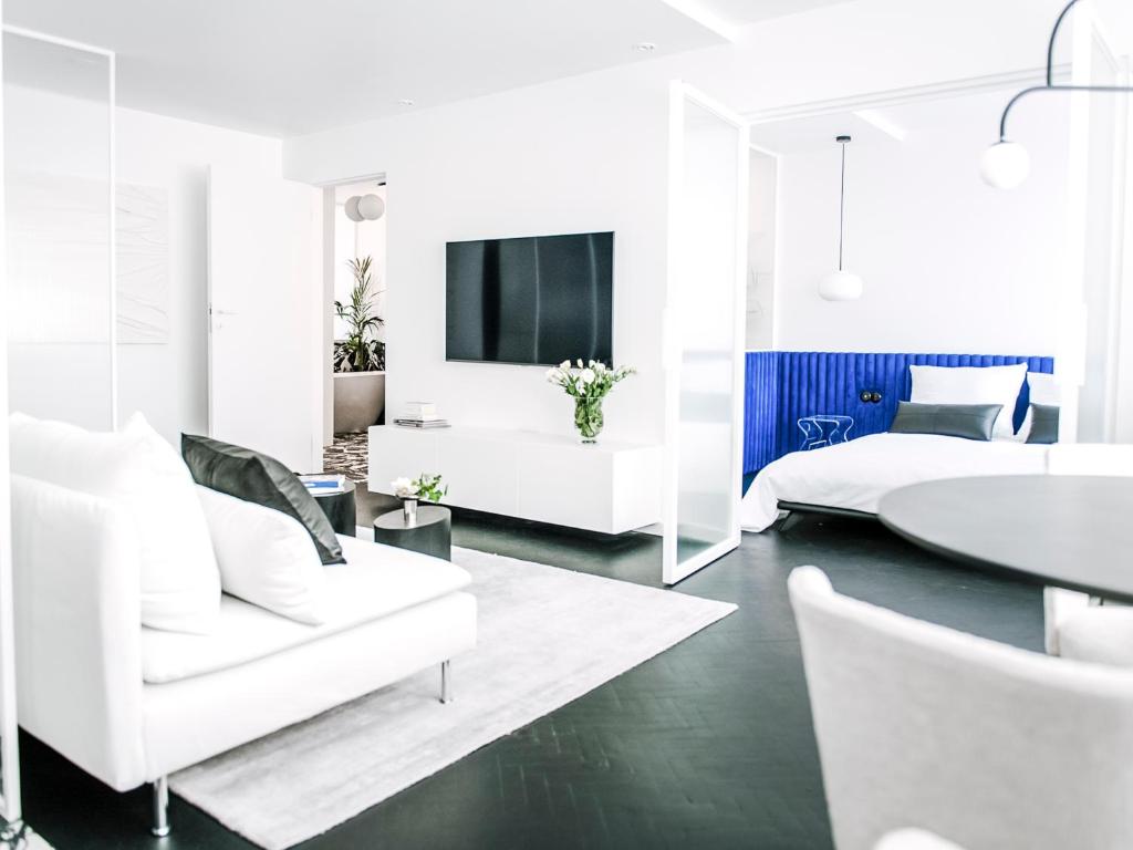 a living room with white furniture and a tv at Pastel Blue Silesian Place Apartments in Katowice