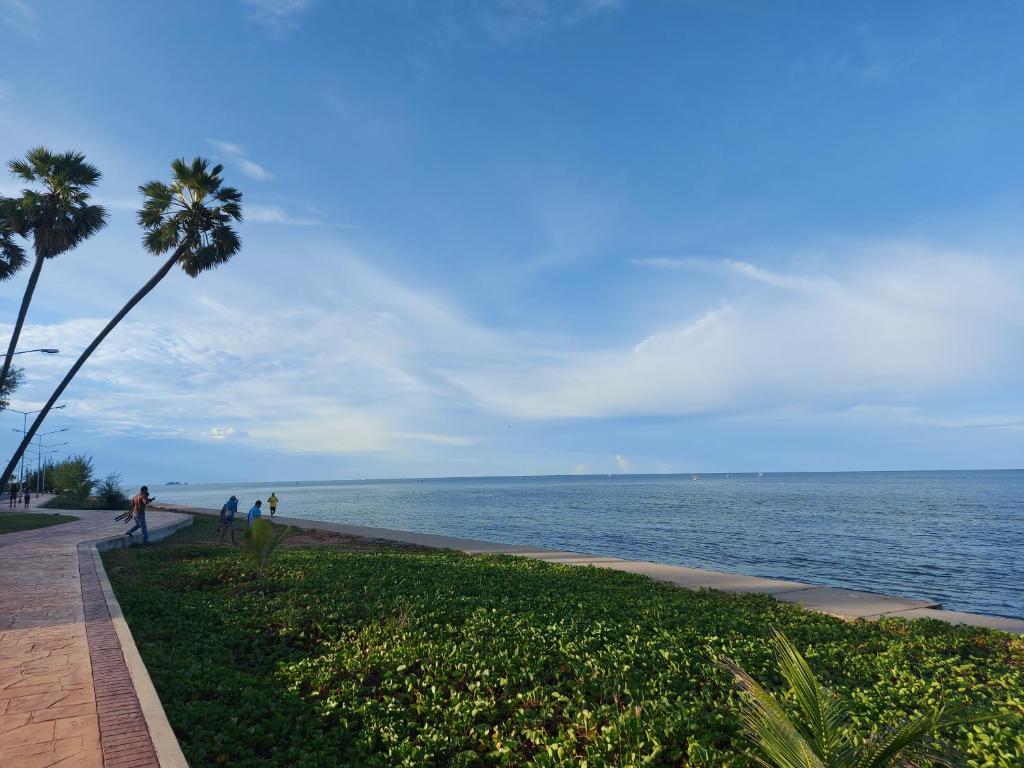 people walking on a sidewalk next to the ocean at Pattawia Resort & Spa, Pranburi in Pran Buri