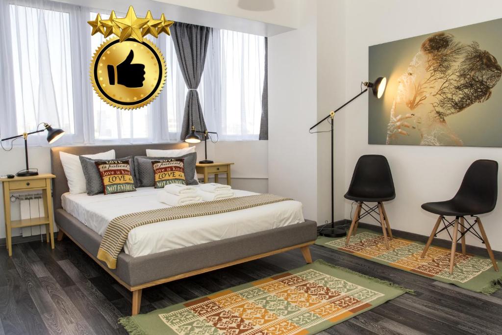 a bedroom with a bed and two chairs at Studio L by MRG Apartments in Bucharest