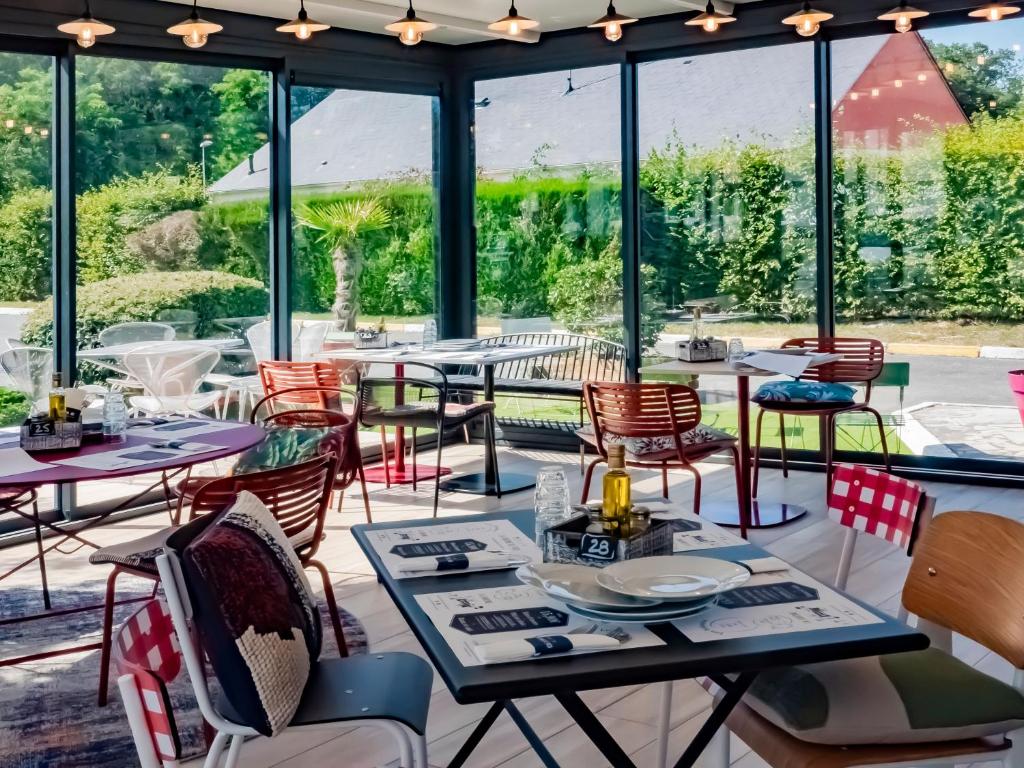 un restaurant avec des tables, des chaises et des fenêtres dans l'établissement ibis Orléans Nord Saran, à Saran