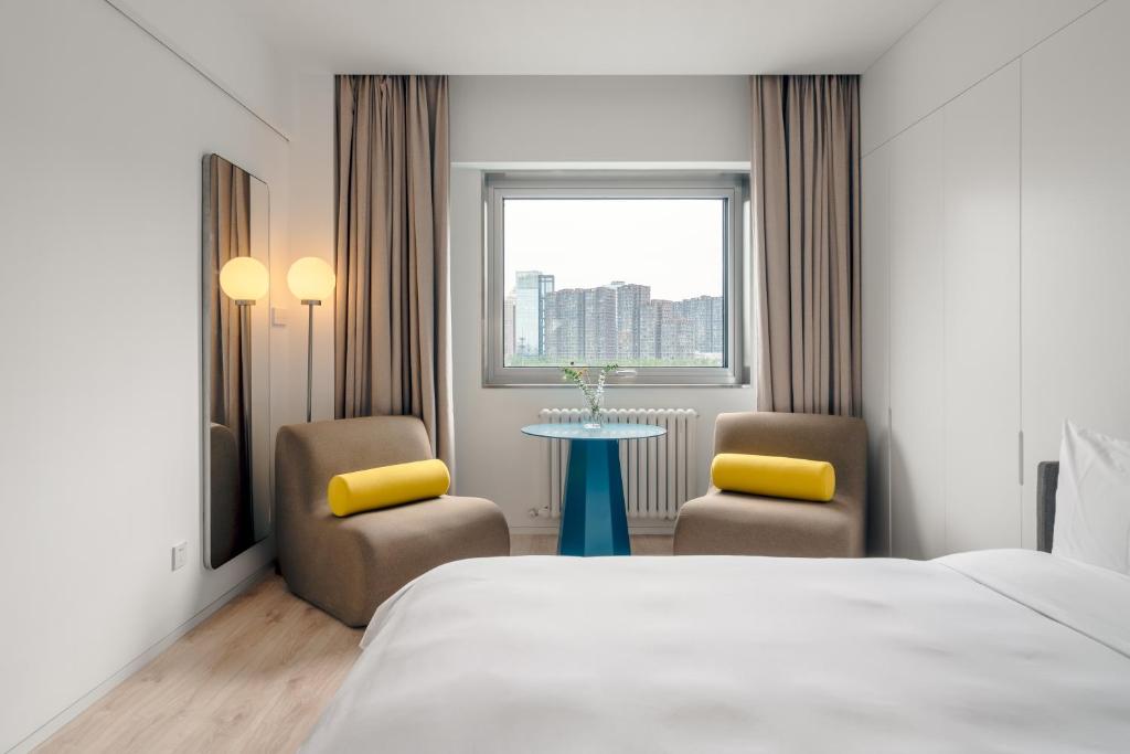 um quarto de hotel com uma cama e duas cadeiras e uma mesa em Stey 798 Art Zone Hotel em Pequim