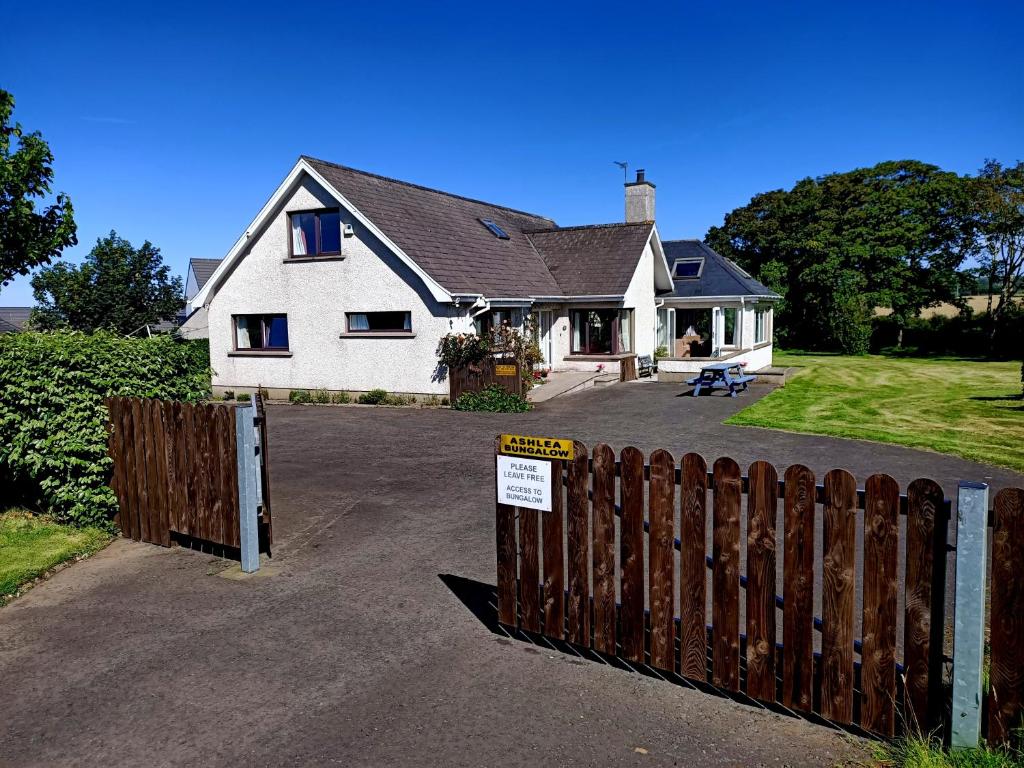 a house with a wooden fence and a gate at Ashlea Bungalow in Portrush