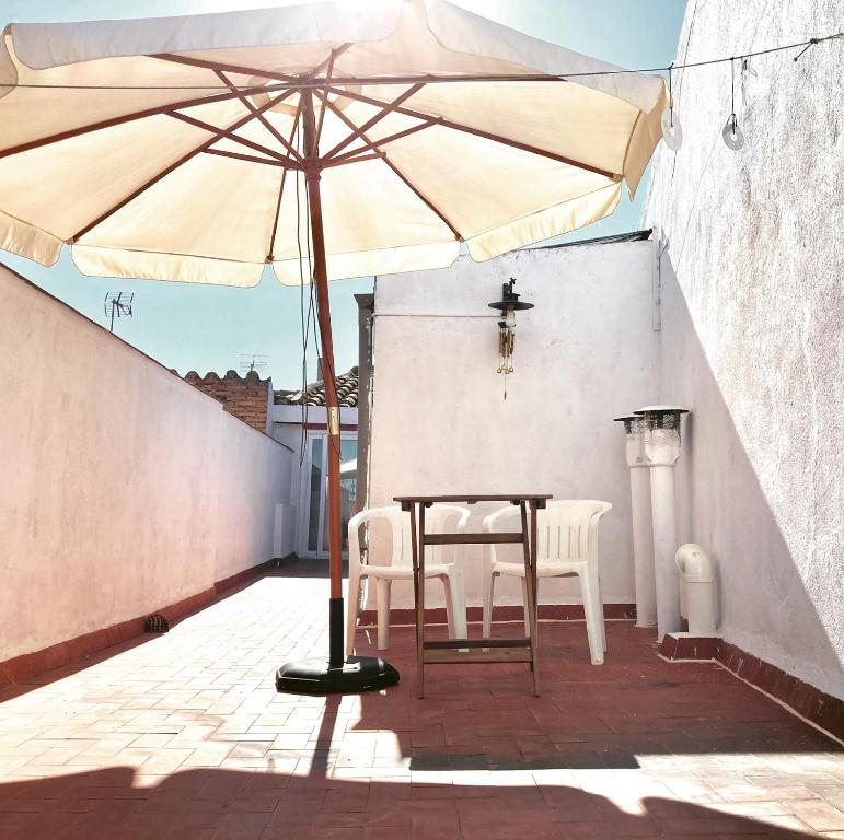 a table and chairs under an umbrella on a patio at Casa Taller Penelles in Penellas