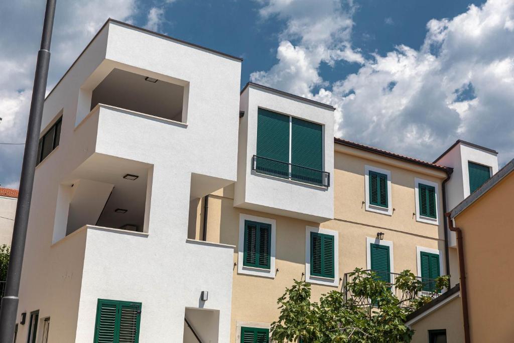 a building with white and green shutters on it at APARTMANI VIGO in Crikvenica