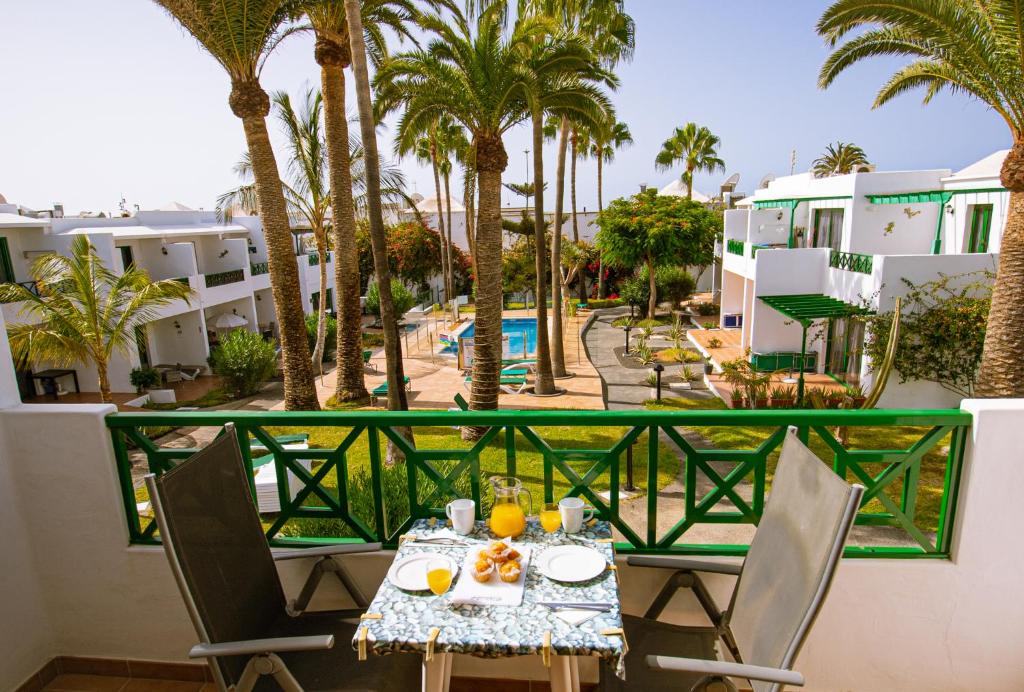 einen Tisch und Stühle auf einem Balkon mit Palmen in der Unterkunft Paradise Club in Puerto del Carmen