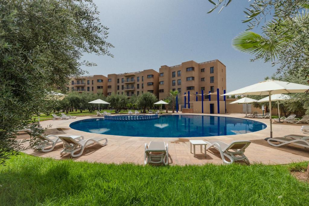 a swimming pool with chairs and umbrellas at Wazo Appart-Hôtel in Marrakech