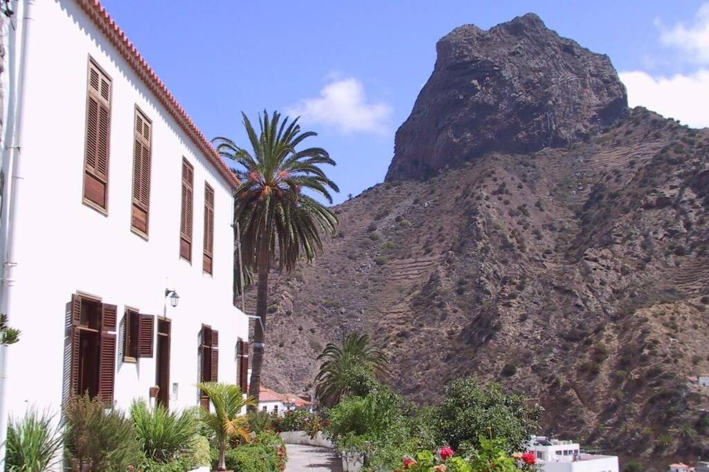 a mountain next to a building with a palm tree at Casa Karen in Vallehermoso