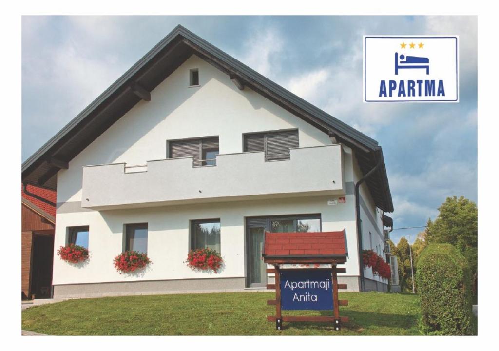 a white house with a sign in front of it at Apartmaji Anita in Begunje pri Cerknici