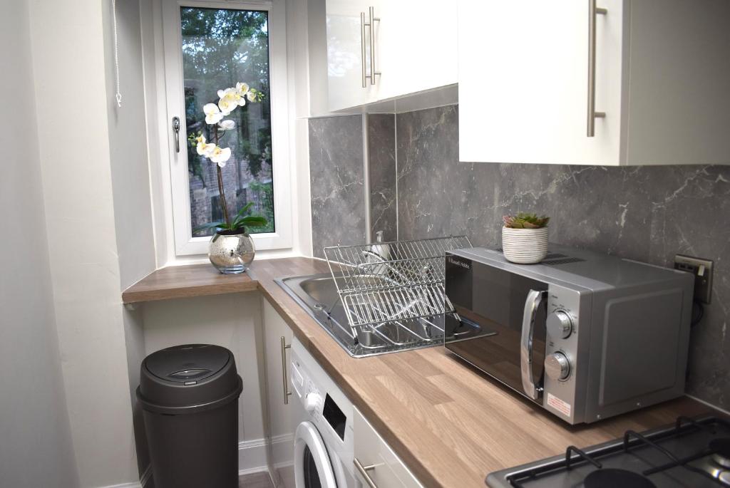
a kitchen with a stove top oven and a microwave at Kelpies Serviced Apartments- Victoria in Falkirk
