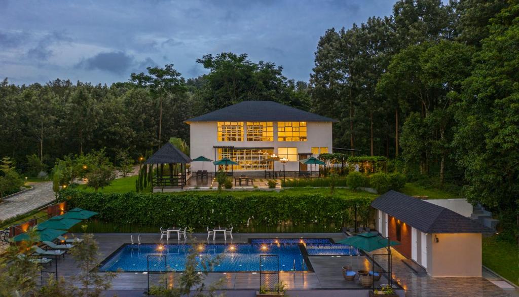 ein Haus mit einem Pool vor einem Gebäude in der Unterkunft Vismita County in Chikmagalur