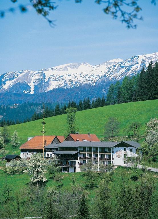 a building in the middle of a field with snow covered mountains at Ausflugshotel Huttersberg in Kirchdorf an der Krems