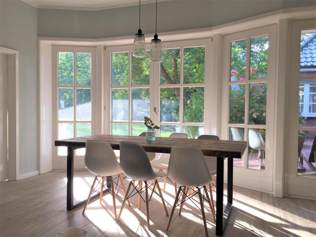 a dining room with a wooden table and white chairs at Uns Landhus 43 - 5 Personen in Tating