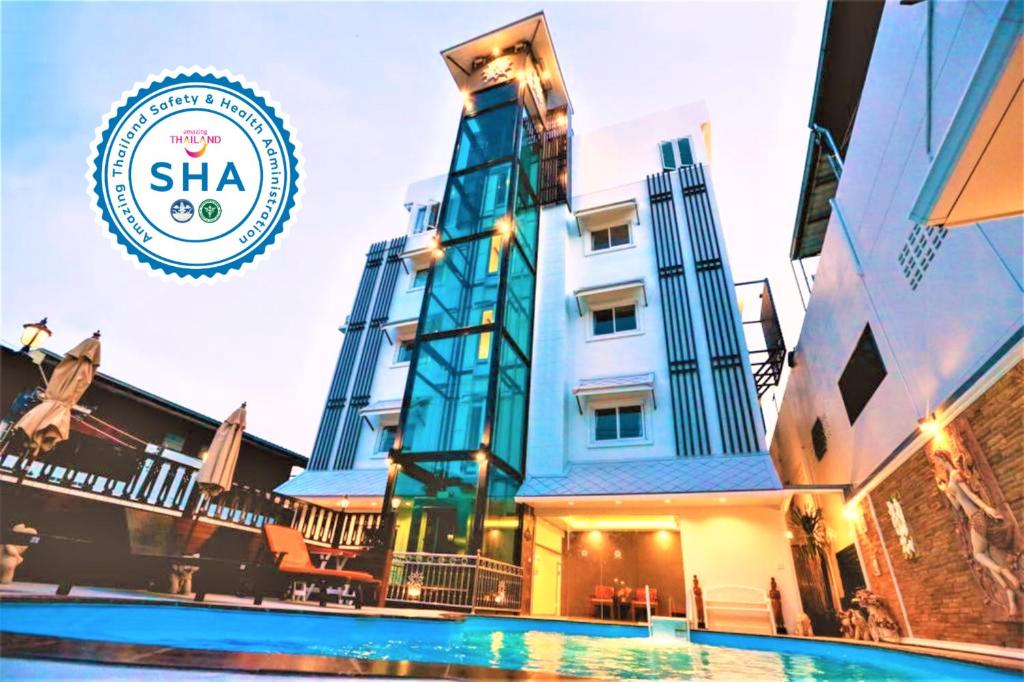 a hotel with a swimming pool in front of a building at Hua Hin White Villa Hotel - SHA Certified in Hua Hin