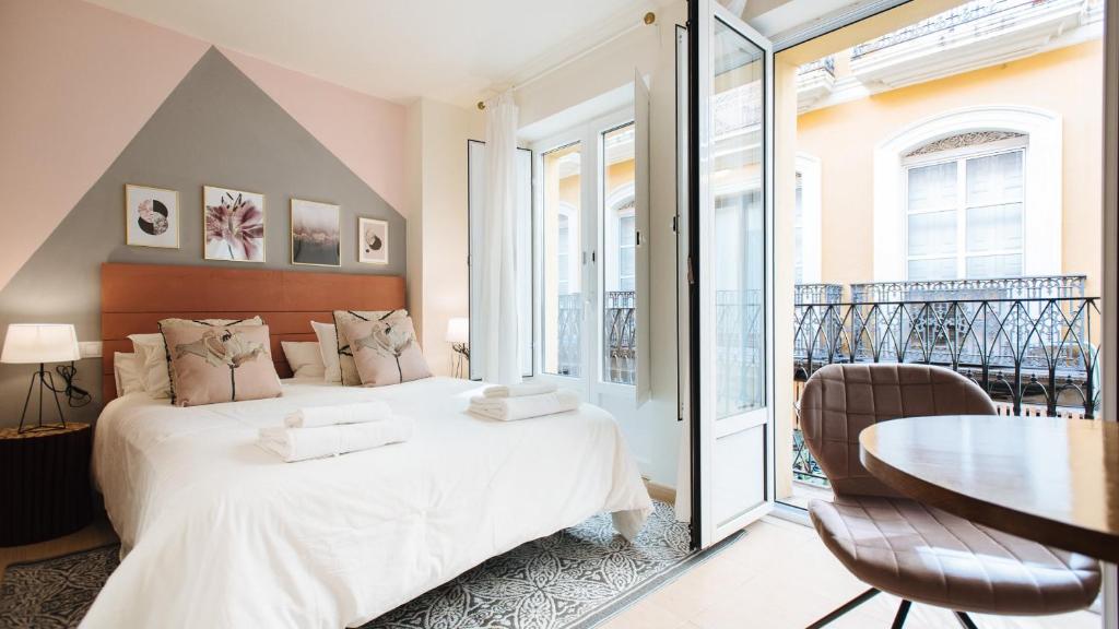 1 dormitorio con cama blanca y mesa en Lineros - Apartments with shared Rooftop en Sevilla