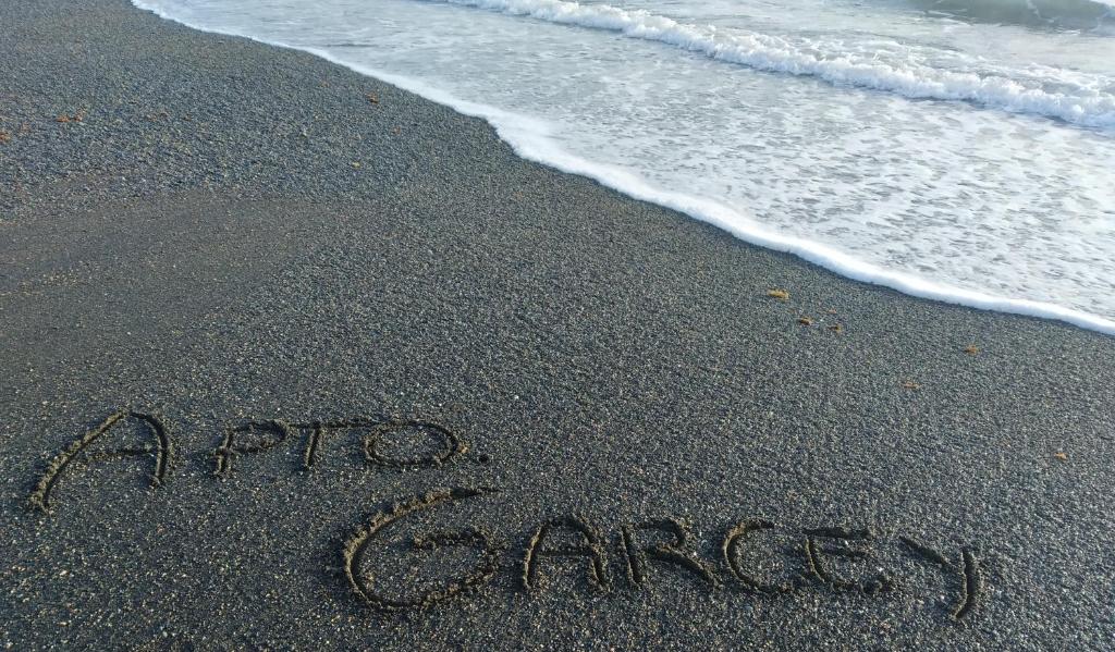 a sign written in the sand on the beach at Apartamento Garcey in Ajuy