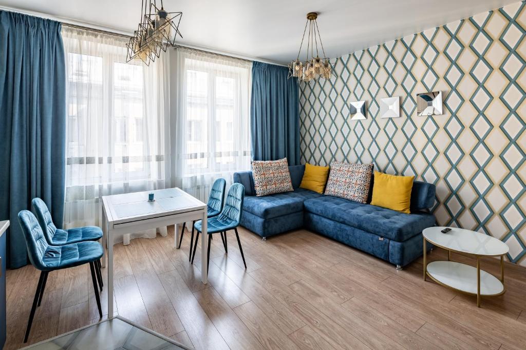 ein Wohnzimmer mit einem blauen Sofa und Stühlen in der Unterkunft Romari Гнатюка 3 in Lwiw