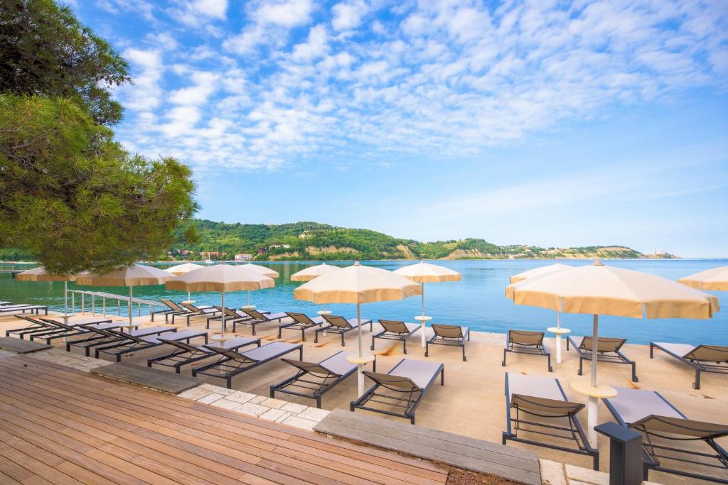 un gruppo di sedie e ombrelloni accanto all'acqua di Holiday Park Vile - Terme Krka a Strunjan