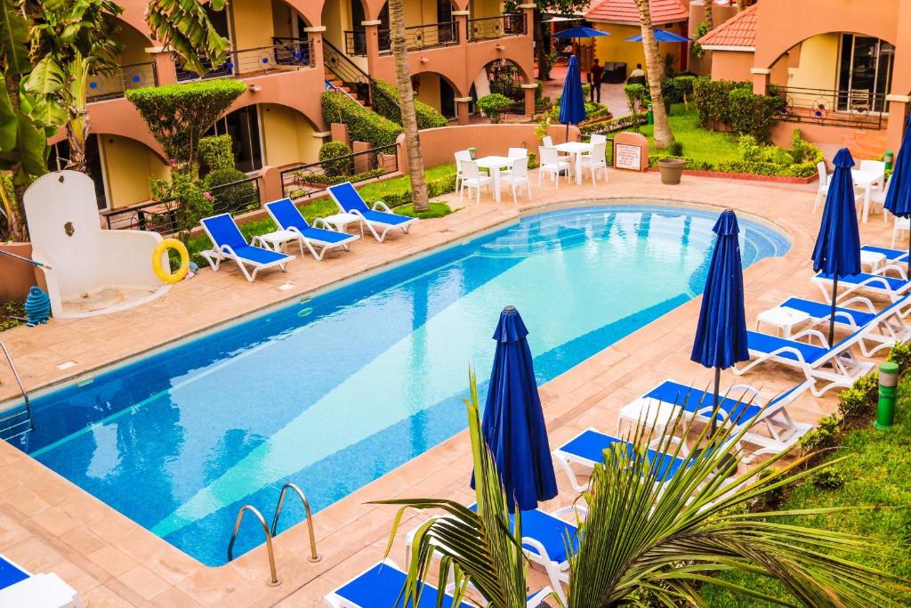 a swimming pool with blue umbrellas and lounge chairs at Airport Hotel Casino du Cap-vert in Dakar