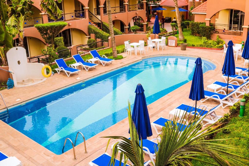 einen Pool mit blauen Sonnenschirmen und Liegestühlen in der Unterkunft Airport Hotel Casino du Cap-vert in Dakar