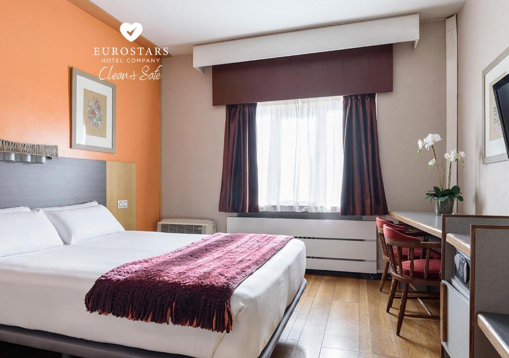 una camera d'albergo con un grande letto e una scrivania di Crisol Quindós a León