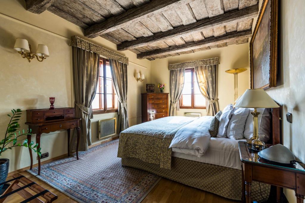 a bedroom with a bed and a table and windows at Golden Well in Prague