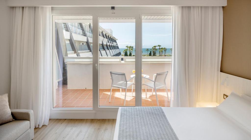 a bedroom with a bed and a balcony with a table and chairs at Ilunion Islantilla in Islantilla
