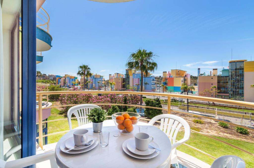 a table with cups and oranges on top of a balcony at Apartamentos da Orada by Garvetur in Albufeira