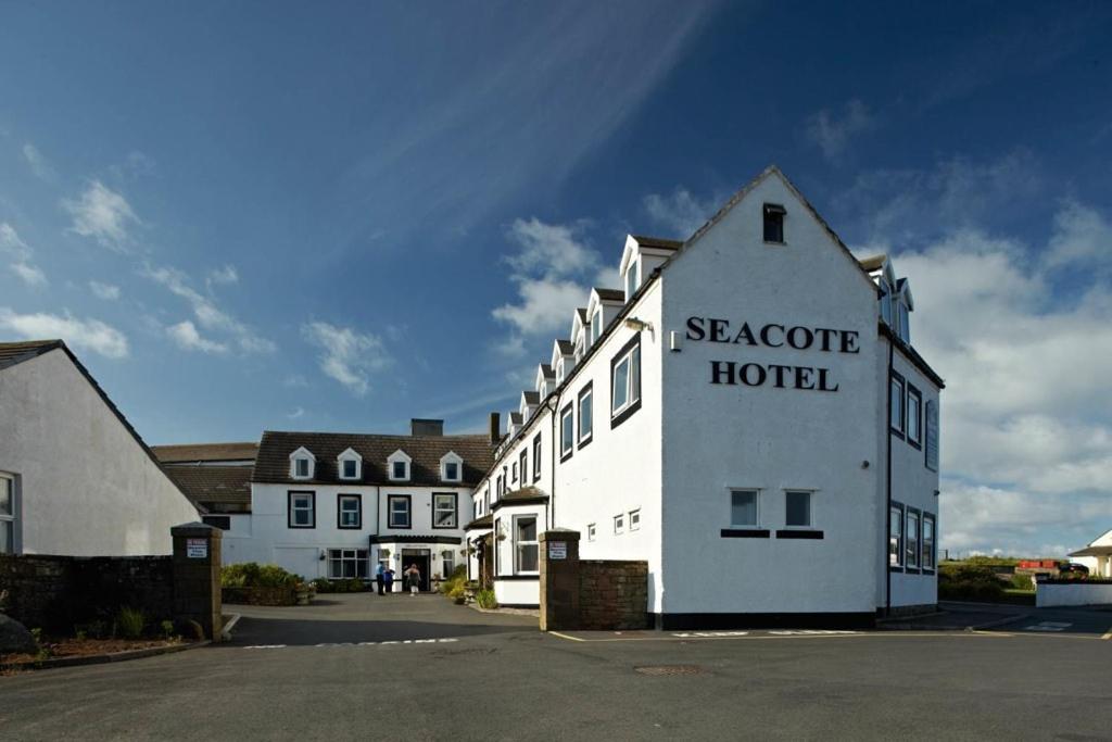 um edifício branco com as palavras Scarcombe hotel sobre ele em Seacote Hotel em St Bees