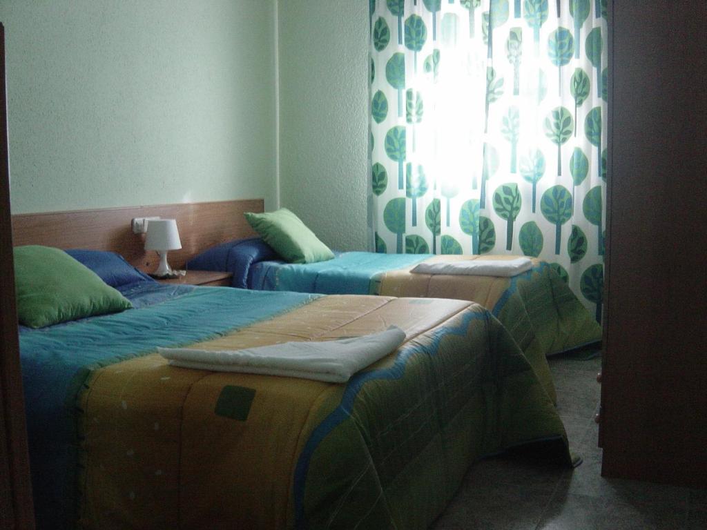 una habitación con dos camas y una ventana en Hostal Emilio Barajas, en Madrid