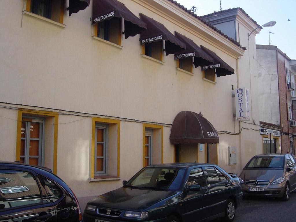 dos coches estacionados frente a un edificio en Hostal Emilio Barajas, en Madrid