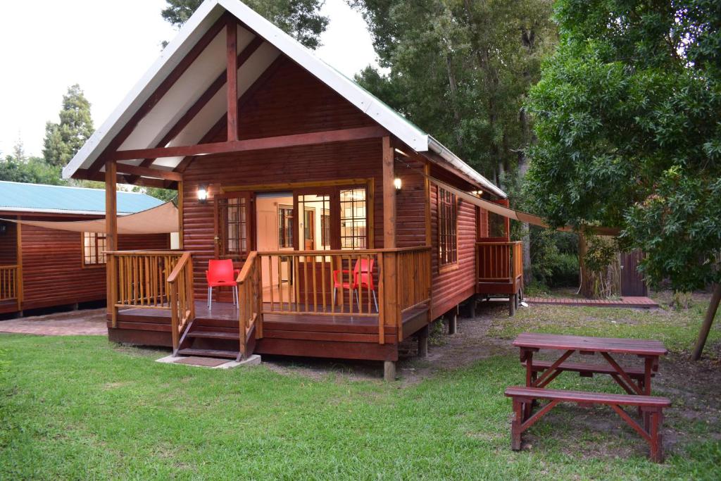 een houten hut met een picknicktafel ervoor bij Mad About Saffron in Stormsrivier