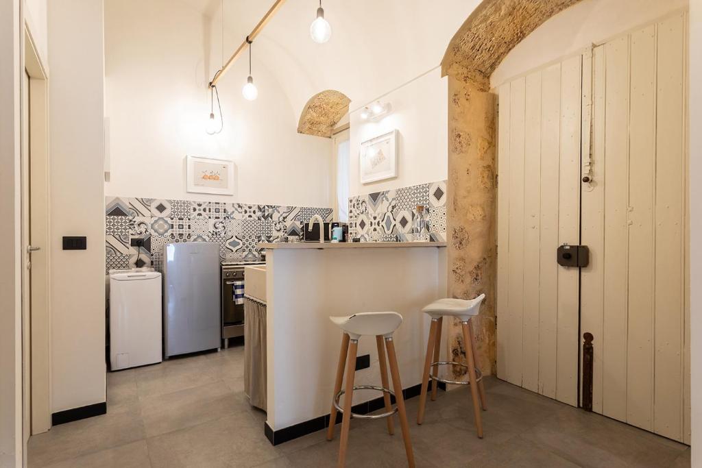 una cucina con bancone e sgabelli in una stanza di Biancospino Suite by Wonderful Italy a Noto